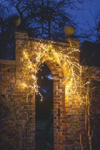 Weihnachtsbeleuchtung rund um ein gewölbtes Tor im Freien
