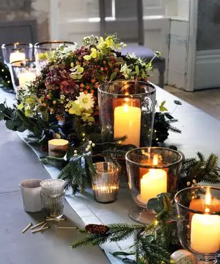 Ideas para centros de mesa de Acción de Gracias con un corredor de follaje de pino con centro de mesa floral y velas