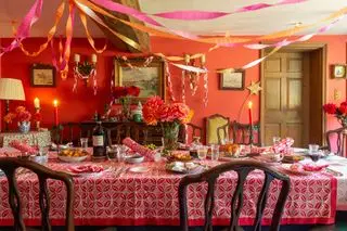 Comedor navideño con mantel Molly Mahon con estampado de bloques, serpentinas de papel en el techo y cadenas de papel