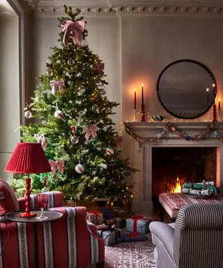 暖炉のあるリビングルーム、丸い鏡、リボン付きのクリスマスツリー