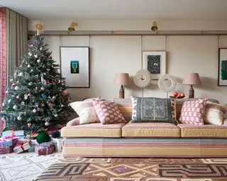 大きな縞模様のソファとクッション、クリスマス ツリー、幾何学的な敷物を備えたモダンなリビング ルーム