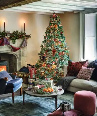 装飾されたクリスマス ツリー、暖炉、床にクッション、ソファのある居心地の良いリビング ルーム