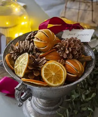Schüssel auf Fuß mit Orangenscheiben und Tannenzapfen