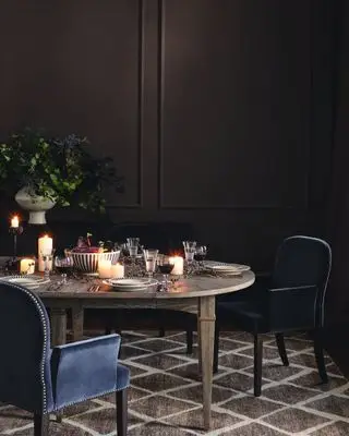 spisestue med vegger i mørk sjokolade, marinestoler, borddekor i høststil, svarte og hvite tallerkener, stearinlys, vase med blomster og bær