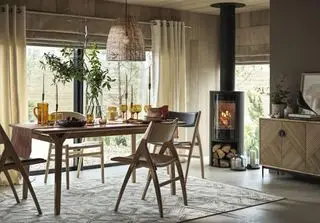 høstens spisestue med møbler i retrostil, vedovn, teppe, lampeskjerm i rotting, ravfarget glass, skjenk