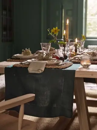høstborddekking med grønn løper, kremtallerkener, stearinlys, telys, grønnmalte vegger