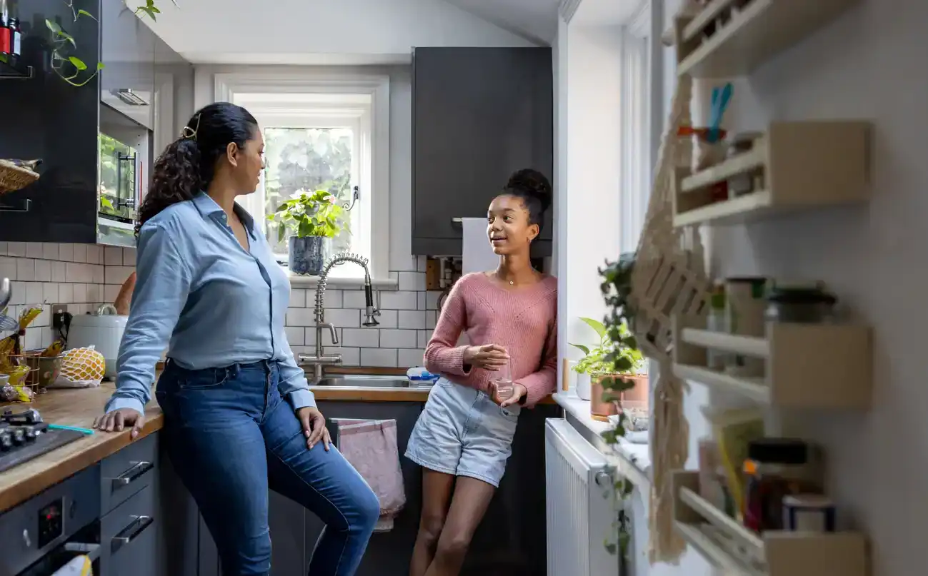 Happy mother and daughter bonding at home in the kitchen and talking - family concepts