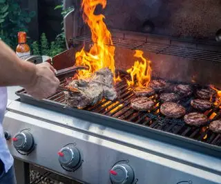 Grillning af lam og burgere på en stor gasgrill