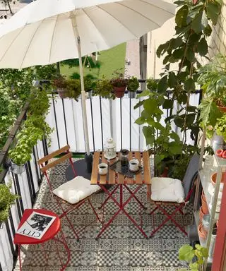 petit patio avec une table et des chaises et un parasol blanc