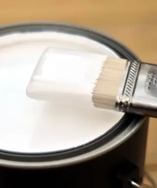 開いた白いペンキの缶の上に絵筆を置く