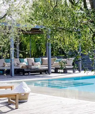 Et poolområde med et overdækket terrasseområde og en stor udendørs sofa