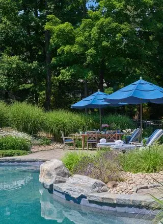 terrasse ved siden af ​​poolen med liggestole, bord, stole og paraply