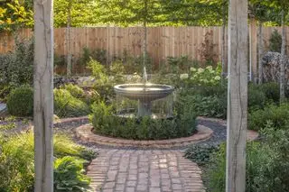 kaskadehavespringvand i terrasse med beplantning og hæk