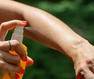 borrifando spray mosquito no braço