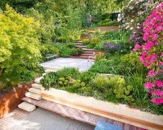 Mehrstöckiger Garten mit Holzstufen, rosa Blumen, Bäumen und Pflanzen