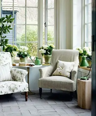 Ideen für Gartenzimmer mit Einrichtung im Landhausstil, zwei Sesseln, Steinboden, Pflanzen und Blumen auf der Fensterbank