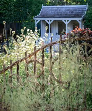 Et eksempel på ideer til sommerhushave med en eng og et rustikt hegn