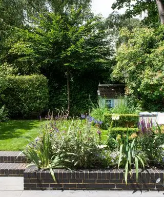 Ein Beispiel für schmale Gartenideen mit gemauerten Blumenbeeten und Stufen, die zu einer Rasenfläche führen.