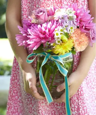 Ideen für eine Gartenparty mit einem jungen Mädchen, das ein Glas Blumen in der Hand hält