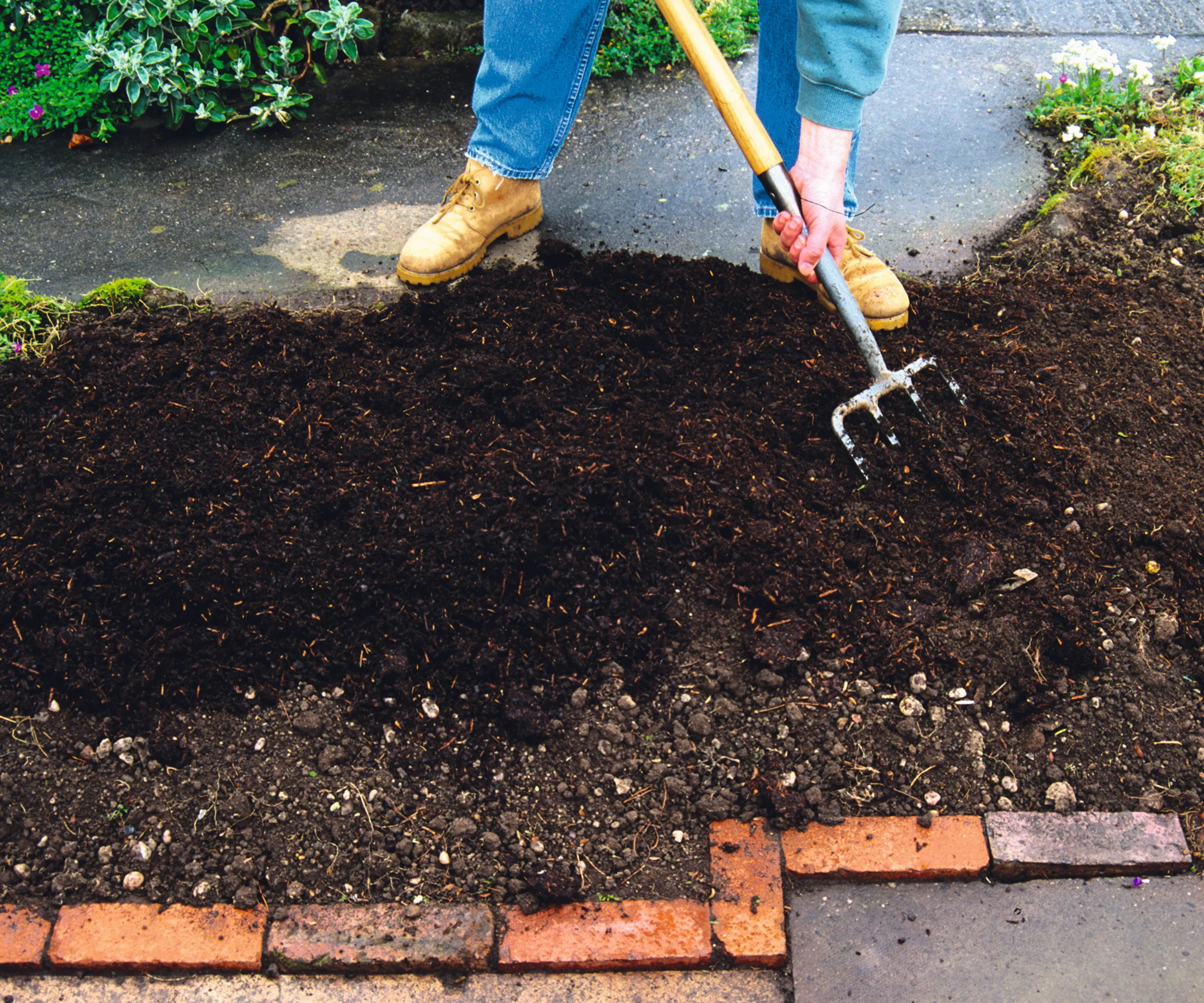 Tilføjelse af kompost til et havebed med en gaffel' loading='lazy' title=