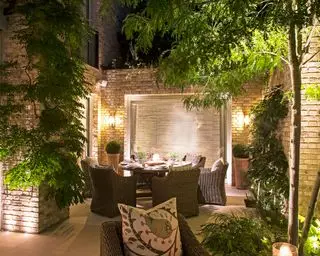 jardim no pátio com área de jantar ao ar livre iluminada à noite