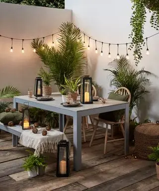 Innenhofterrasse mit Lichterketten, die an weiß gestrichenen Wänden hängen