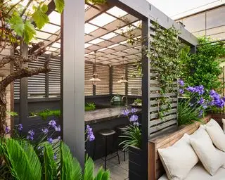 áreas para sentarse divididas en zonas debajo de una pérgola en un patio trasero