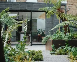 una terraza en el patio trasero con maceteros de acero corten y puertas de patio de crittal