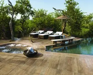 Una piscina al aire libre y jacuzzi en un jardín tropical con tumbonas