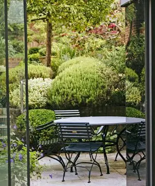 Pequeño jardín en terrazas inclinado con zona para sentarse en la parte inferior.