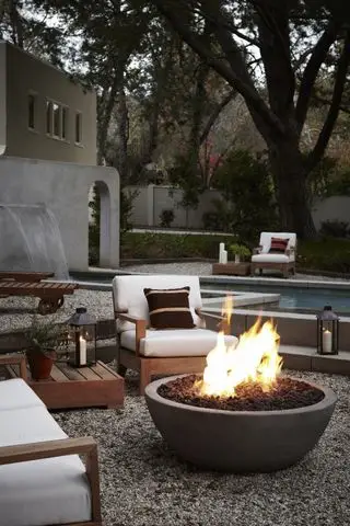 Feuerstelle auf der Terrasse, umgeben von Gartensesseln