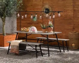 Terrasse mit Esstisch und Bänken sowie Lichterketten im Freien