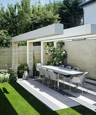 Moderne Ideen für Terrassenmöbel aus Metall, demonstriert durch einen langen Tisch und Stühle unter einem markanten architektonischen Element.