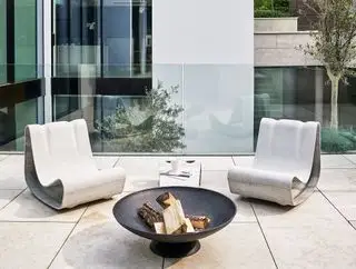 Moderne Ideen für Terrassenmöbel für den Außenbereich mit zwei skulpturalen Metallstühlen vor einer Feuerstelle.