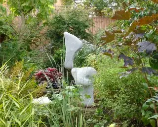Escultura equilibrada de piedra de Adrian Gray en un jardín