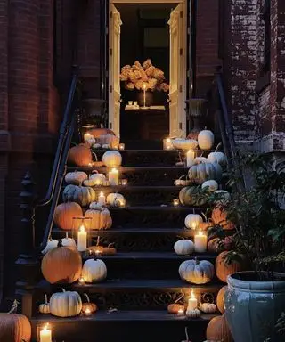 Ideias de decoração de portas de Halloween com abóboras e velas em vasos de furacão alinhados em ambos os lados das portas
