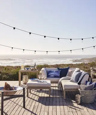 En treterrasse med en utendørs sofa med utsikt over et hav