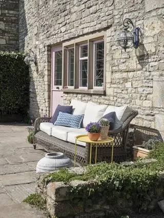 Außenseite des Cottages mit Steinplattenböden und Rattansofa