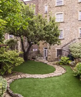 un camino de piedra que se curva hacia un jardín inclinado
