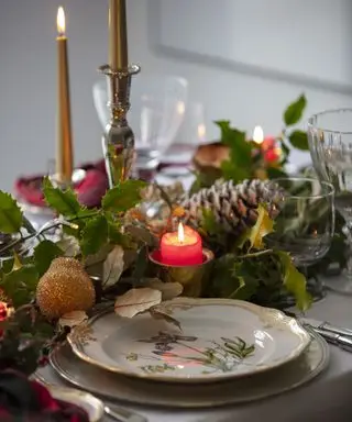 Una tavola di Natale decorata con una ghirlanda di abete rosso di foglie verdi e pigne
