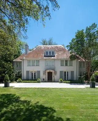 Extérieur d'une maison de style français des années 1920 avec toit en ardoise et ailes de chaque côté d'une façade symétrique