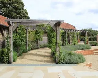 pergola ve venkovské zahradě podél okraje kruhové terasy navržené Bowles & Wyer