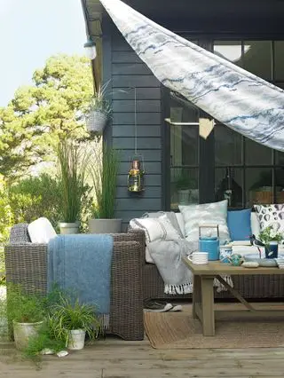 Terrasse mit bunten blauen Segeln und Gartenmöbeln