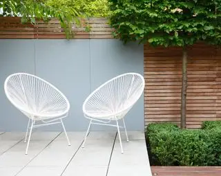 Sedie bianche e sottili illustrano come progettare un piccolo giardino
