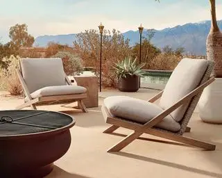 Et par loungestole i teak- og rattaneffekt på en solterrasse ved en pool