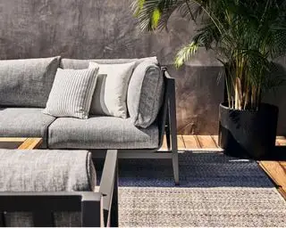 En sort pulverlakeret udendørs sofa i aluminium med polstrede grå sædehynder fra Outer