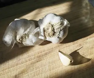 Dois dentes de alho de uma loja em uma tábua de cozinha de madeira