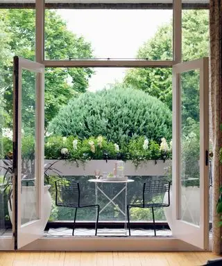 Esempio di idee per il giardino sul balcone con tavolino e sedie da bistrot che si affacciano sulle fioriere della finestra.