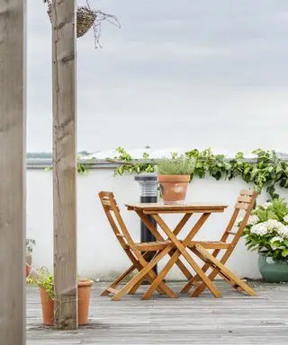 Eine Dachterrasse mit einem kleinen Holztisch und Stühlen neben einer Solarlampe
