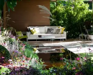capas suaves de plantas perennes alrededor de un patio cubierto con fuente de agua